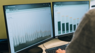 Close-up of two monitors showing data visualizations from the VENI Customer Portal.